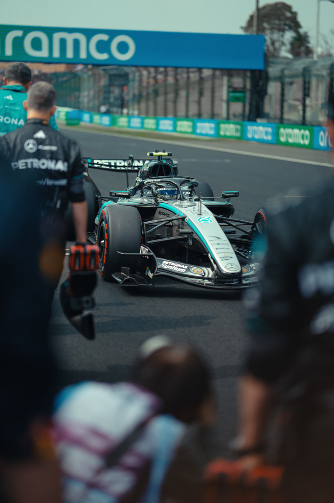 Mercedes F1 car in pit lane surrounded by team