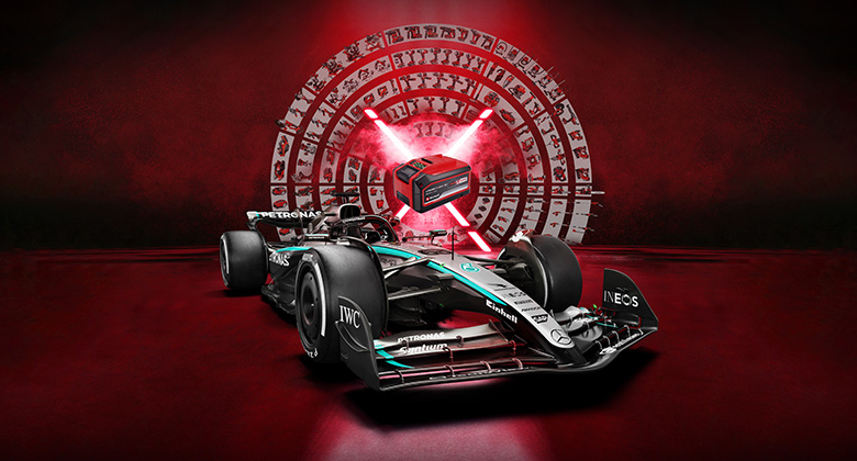 En Mercedes-AMG PETRONAS Formel 1-bil står mot en lysande röd bakgrund med ett Einhell-batteri i mitten. Einhell- och Mercedes-AMG PETRONAS F1 Team-logotyperna visas i det nedre högra hörnet.