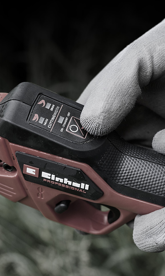 Närbild på en röd Einhell sladdlös produkt med en handskbeklädd hand som justerar dess läge.