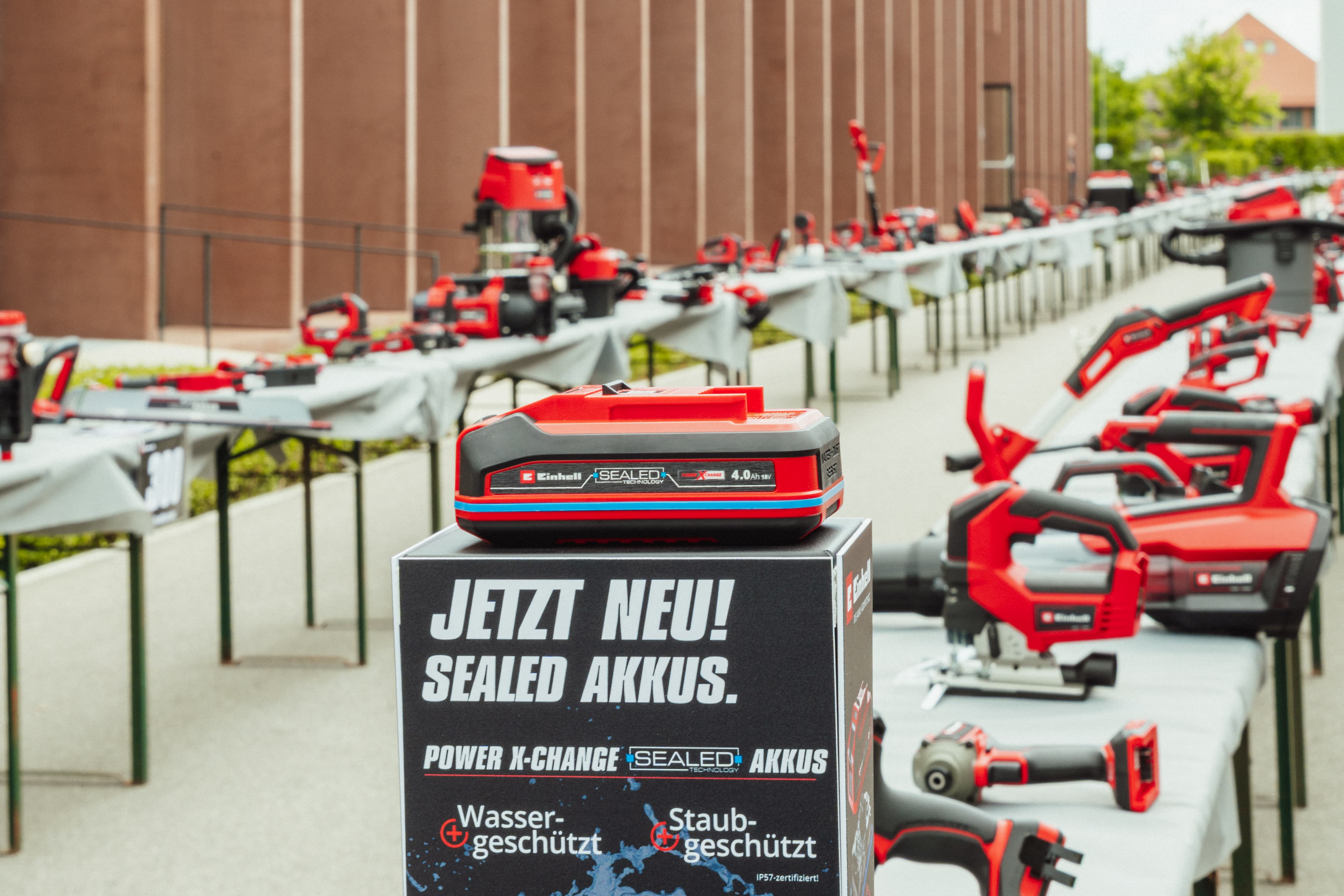 An Einhell SEALED battery Power X-Change 4.0 Ah on a display reading: “JETZT NEU! SEALED AKKUS”.